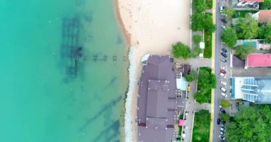 Gelendzhik 'in çakıl taşı plajında sayısız güneşlik ve saman şemsiyeler. Temiz yeşil su. Güneşi. İnsanlar yüzer ve güneşlenir.