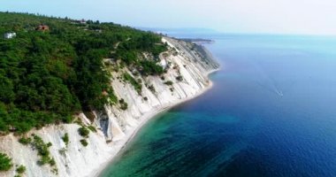 Denizin kayalık kıyısı boyunca ve Karadeniz 'deki Gelendzhik tatil beldesi yakınlarında uçuş. Ağaçlarla kaplı yüksek katmanlı kayalar. Arka planda Blue Bay, Gelendzhik, Kafkasya dağları. Temizle