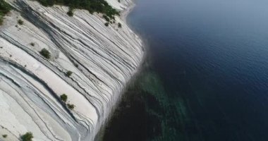 Açık güneşli bir havada Karadeniz kıyısındaki beyaz uçurumların üzerinden uçuyorlar. Kayalıkların dibinde çakıl taşı plajı. Mavi, pürüzsüz deniz. Çam ağaçları orada burada, kayalıklarda yetişir.