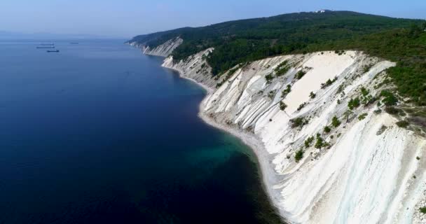 Let nad Černým mořem z Gelendzhiku do Novorossiysku. Dron přeletí vysoké svažující se skály vrstvené skály. Hory jsou pokryty borovicemi. Malá oblázková pláž na úpatí — Stock video