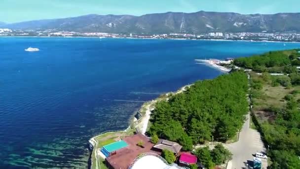 La località di Gelendzhik, Capo "Grasso". Yacht, jet ski tira una banana con i passeggeri sullo sfondo del faro Gelendzhik e le montagne del Caucaso. Alte rocce e la cupola di un night club — Video Stock