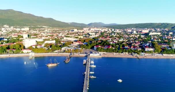 Flug entlang des zentralen Teils des Kurortes Gelendzhik. Blick vom Meer. Wir fliegen den Sandstrand entlang, den zentralen Platz und das Verwaltungsgebäude. Ein großer Pier, an dem Yachten und Schiffe liegen — Stockvideo