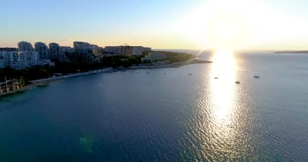 The resort of Gelendzhik. Thick Cape at sunset. The drone flies up to the beach and promenade of the resort at sunset. There are houses behind the embankment. A large body of water with a city in the — Stock Video