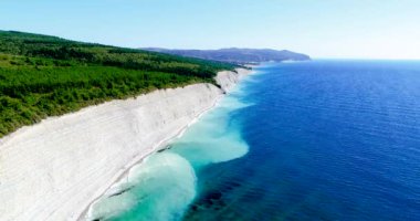 Karadeniz kıyısındaki kayalar ve çakıllı plajlar Noumea 'dan kıyı boyunca uzanan havaalanına doğru giderken. Sahildeki beyaz katmanlı kayaların üzerinde uçuyor. Yukarıdan, kayalar...