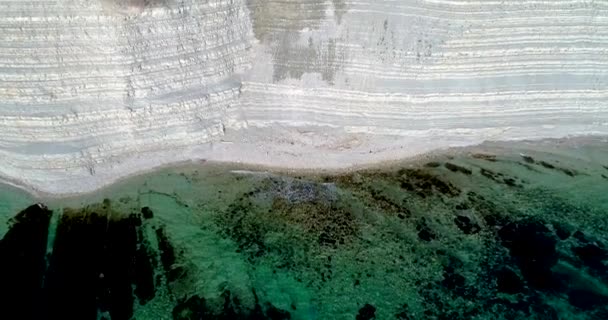 Repülés a Fekete-tenger partjainál Gelendzhik közelében. Partvidék magas, fehér kőzetrétegű szerkezettel. Van egy erdő a sziklákon. Van egy keskeny kavicsos strand a tengerparton. Sima kék átlátszó tenger — Stock videók