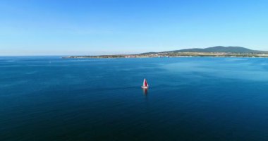 Kırmızı yelkenli altında güzel büyük beyaz bir yat Gelendzhik Körfezi boyunca Gelendzhik tatil beldesinin arka planına doğru yavaşça yelken açar. Büyük bir su kütlesi.