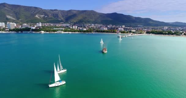 Several beautiful white yachts under sail and a wooden ship depart from the Central pier of the resort of Gelendzhik and go to the exit of the Gelendzhik Bay in the open sea. A large body of water — Stock Video