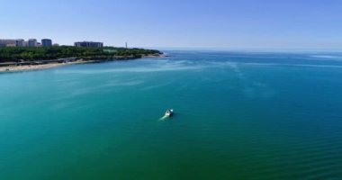 Bir zevk gemisi, Gelendzhik Körfezi boyunca, bir deniz fenerine karşı yavaşça yelken açar. Bir su kütlesinin üstünde bir işaret
