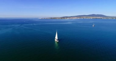 Gelendzhik Körfezi boyunca beyaz yelkenli altında büyük beyaz bir yat, dağlar, Gelendzhik tatil köyü, evler ve plajlara karşı. Dağ olan büyük bir su kütlesi.