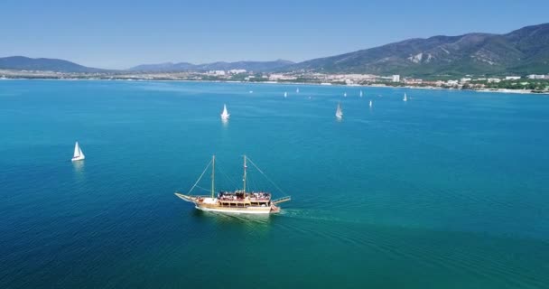 Un barco de madera Pleasure navega a lo largo de la bahía de Gelendzhik en el contexto de las montañas del Cáucaso. Un pequeño barco en un gran cuerpo de agua — Vídeos de Stock