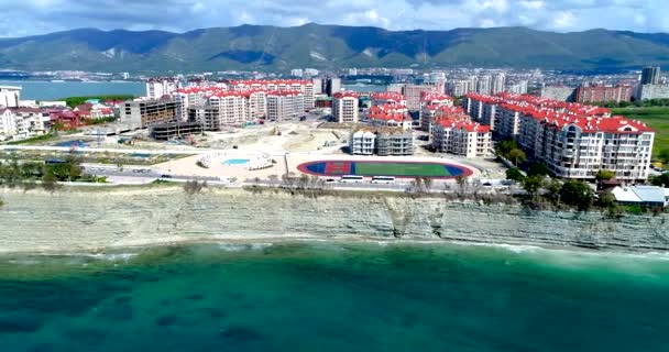 Vuelo en avión no tripulado a lo largo de la costa del mar negro. Alto acantilado rocoso. Una franja de playa de tejas abajo. En la distancia, el faro de Gelendzhik . — Vídeo de stock