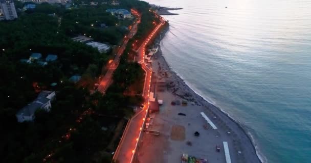 O Resort de Gelendzhik. Voando sobre o resort no crepúsculo da noite. Luzes do aterro e casas, mar escuro, luzes na praia. Um grande corpo de água com uma cidade no fundo — Vídeo de Stock