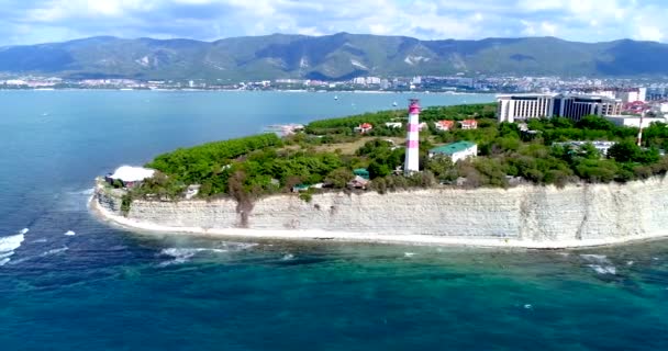 Gelendzhik üdülőhelye. "Vastag" köpeny madártávlatból. Gelendzhik világítótorony, magas szikla. Kis hullámok a tengerben. A háttérben a város, a Gelendzhik-öböl, a Kaukázus hegyei. — Stock videók