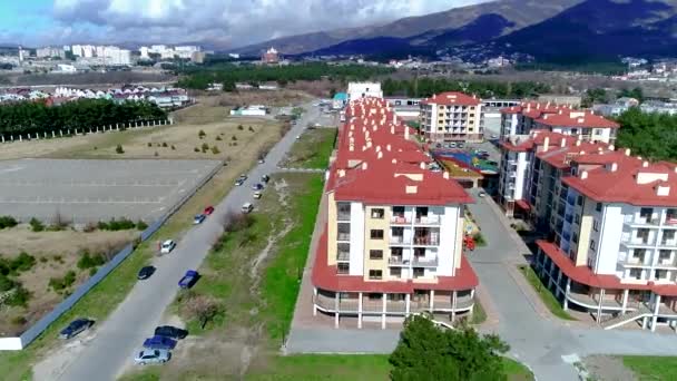 Nowo wybudowany kompleks apartamentowy składający się z kilku wielopiętrowych budynków z czerwonymi dachami. Nagranie z lotu ptaka. Kurort Gelendzhik, morze i góry.. — Wideo stockowe