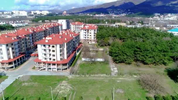 Un complesso di appartamenti di nuova costruzione composto da diversi edifici a più piani con tetti rossi. Video dall'altezza del volo degli uccelli. La località di Gelendzhik, il mare e le montagne .. — Video Stock