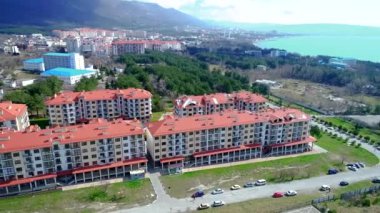 Kırmızı çatıları olan birkaç çok katlı binadan oluşan yeni inşa edilmiş bir apartman. Kuş uçuşu yüksekliğinden bir görüntü. Gelendzhik tatil beldesi, deniz ve dağlar..