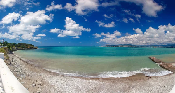 Güneşli bir havada Gelendzhik tatil köyü plajı. Arka planda, Gelendzhik şehri, Körfez ve Kafkasya dağları.