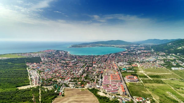 Panorama de Gelendzhik recorre a partir de uma vista panorâmica. Casas e ruas da cidade, Baía de Gelendzhik, as montanhas do Cáucaso à direita. Dia ensolarado, nuvens pequenas — Fotografia de Stock