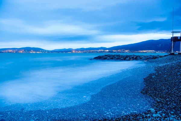 Praia de Gelendzhik de tarde em uma tempestade. As ondas a alta velocidade transformam-se num nevoeiro azul. Tons azuis, inverno. Praia de seixos, quebra-mar . — Fotografia de Stock