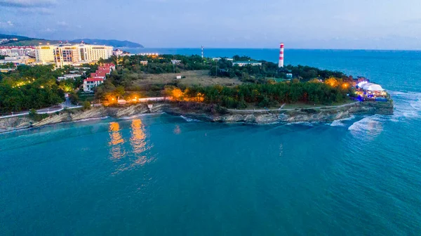 Panorama serale del resort Gelendzhik da una vista a volo d'uccello. "Thick" Cape, faro Gelendzhik. Le luci del terrapieno si riflettono nell'acqua blu scuro Fotografia Stock