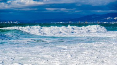 Karadeniz 'de fırtına ve fırtına. Tsemess Körfezi 'nin sularındaki kar beyazı denizden gelen zümrüt fırtınası dalgaları. Novorossiysk ve Kafkas dağları ufukta görünüyor.
