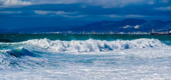 Storm en storm in de Zwarte Zee. Emerald storm golven van de sneeuw-witte zee in de wateren van de Tsemess Bay. Novorossiysk en de Kaukasus bergen aan de horizon — Stockfoto