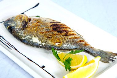Izgara Dorado. Limonlu Dorado kare beyaz bir tabakta. Beyaz arkaplanda