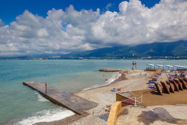 Güneşli bir havada Gelendzhik tatil köyü plajı. Arka planda, Gelendzhik şehri, Körfez ve Kafkasya dağları