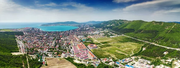 Panorama di Gelendzhik resort da una vista a volo d'uccello. Case e strade della città, Gelendzhik Bay, le montagne del Caucaso sulla destra. Giorno soleggiato, piccole nuvole Immagini Stock Royalty Free