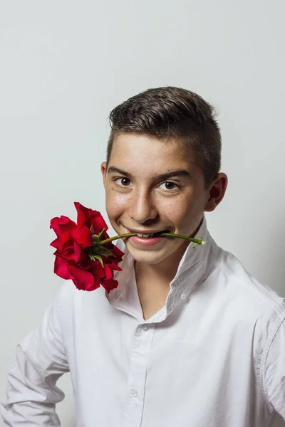 Молодий хлопчик тримає троянду в роті, щоб бути готовим до побачення на кордоні — стокове фото