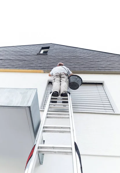 Plasterer staying on ladder and covering the roof underside with — Stock Photo, Image