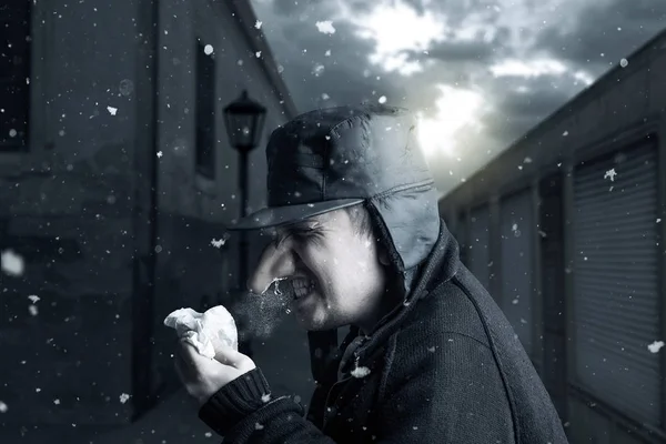 Hombre estornudando en el pañuelo en frente de callejón estrecho en invierno —  Fotos de Stock