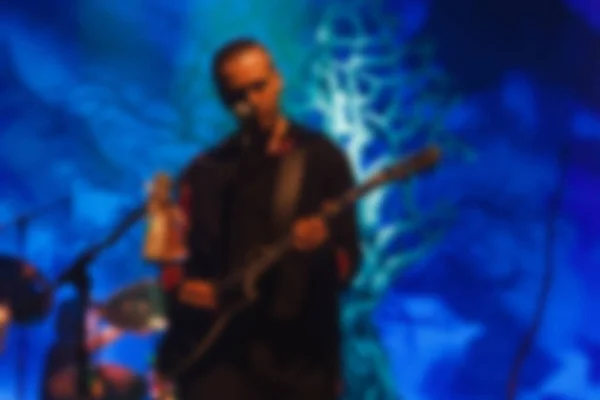 Rock band concert. Musician plays at guitar on the stage. Abstract blurred image