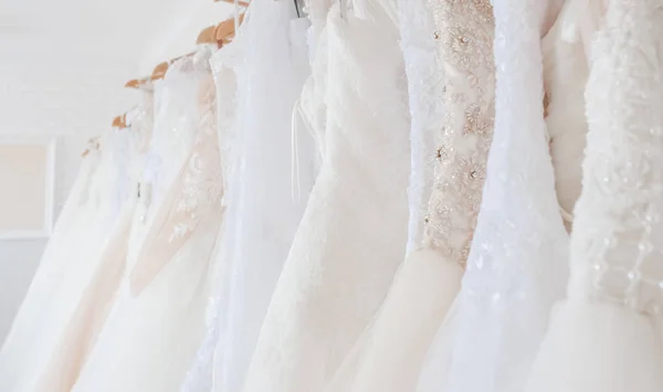 Wedding dresses hanging on a hanger. Interior of bridal salon.