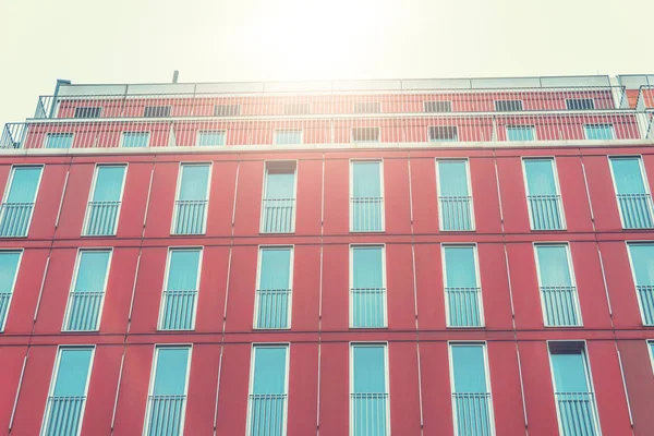 Vermelho fachada edifício de luxo com janelas azuis e luz solar — Fotografia de Stock