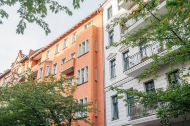 turuncu ve beyaz bina yeşil ağaçlarla çevrili.