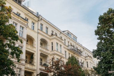 Yeşil ağaçlarla çerçevelenmiş sarı apartman binaları