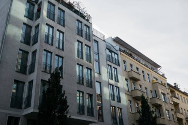 Modern gri ev, diğer sıcak renklerde bir binanın yanında.