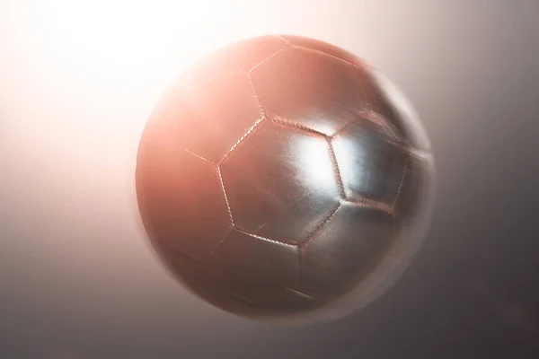 Soccer ball backlit by a bright glow with wraparound flare effect in a close up view