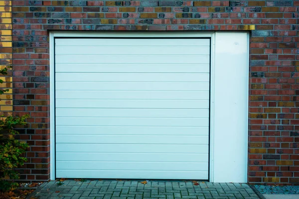 Beyaz garaj kapısı tuğla kaplamalı.