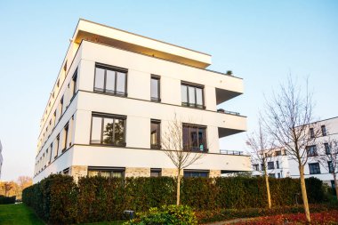 Önünde yeşil çalılar olan beyaz apartman kompleksi