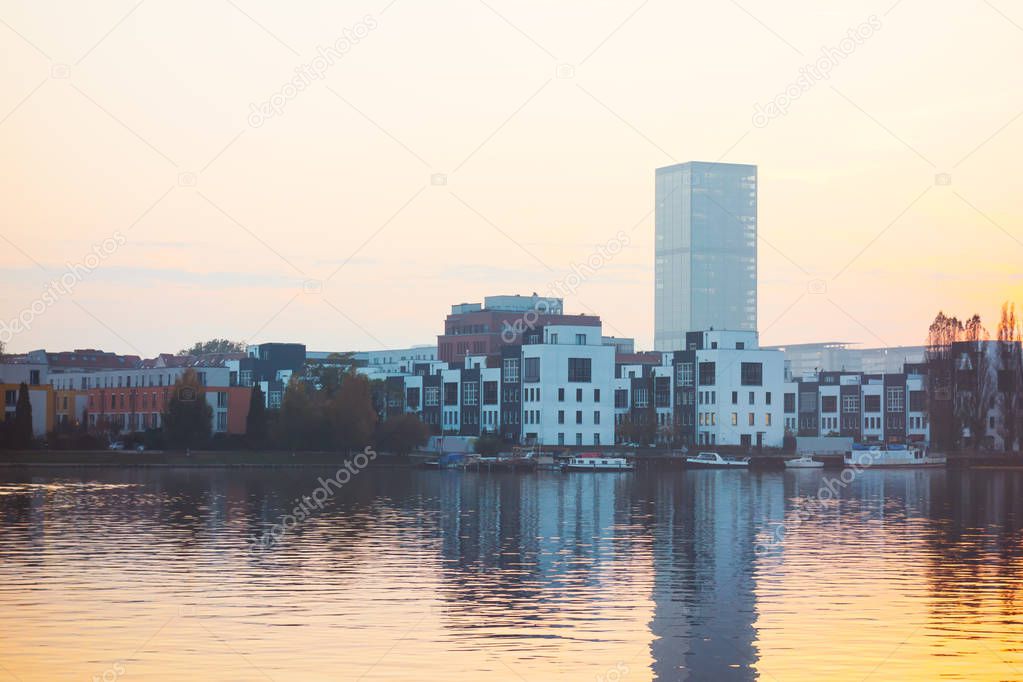spree river in the evening with townhouses and skyscraper in the background at berlin, germany