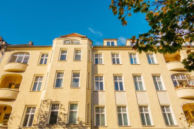 Yeşil ağaçlı sarı apartman dairesi.