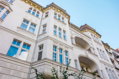 Büyük kıvrımlı balkonlu beyaz yüzlü bir ev.