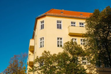 high contrasted orange corner house framed by trees