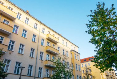 yellow apartment building with green tree in hdr look