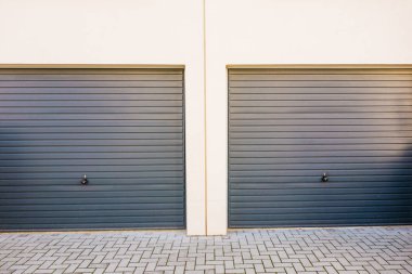 two grey garage doors on white building