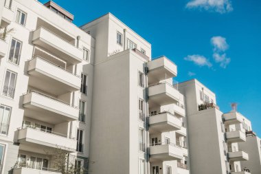 Büyük balkonlu ve kabarık bulutlu modern binalar.