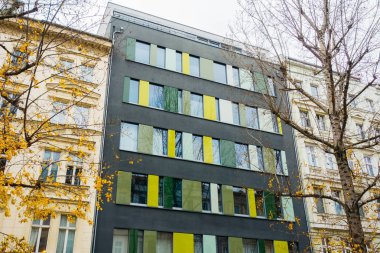Colorful modern grey and yellow apartment block or townhouse complex with autumn trees in the foreground in a low angle view