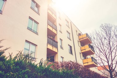 white apartment complex with yellow balcony and sunlight on the top